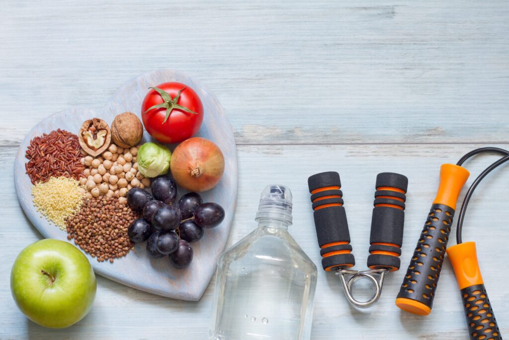 Flatlay with healthy food, water, and exercise equipment.